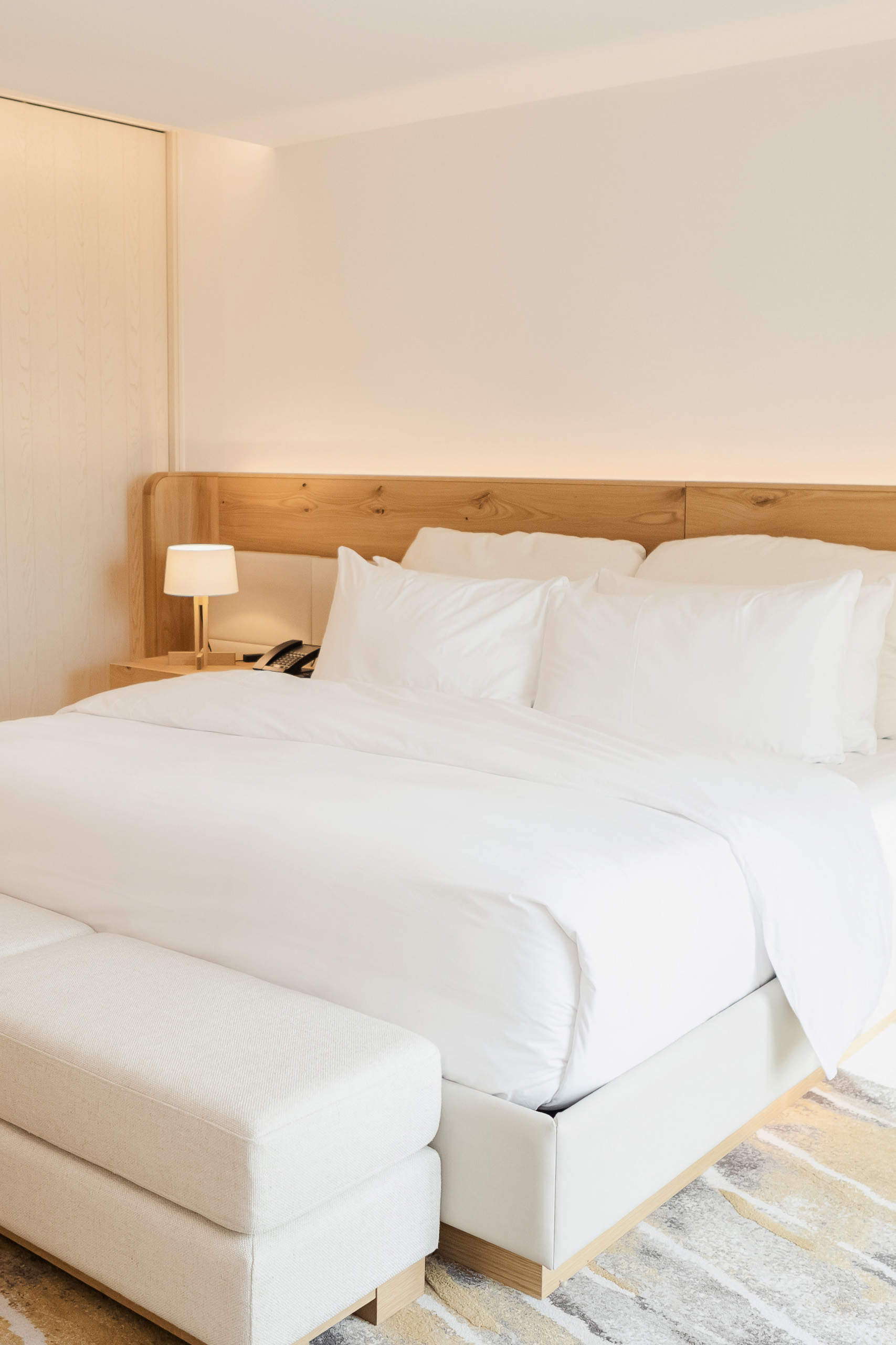 King sized bed with white linens and natural wood head board