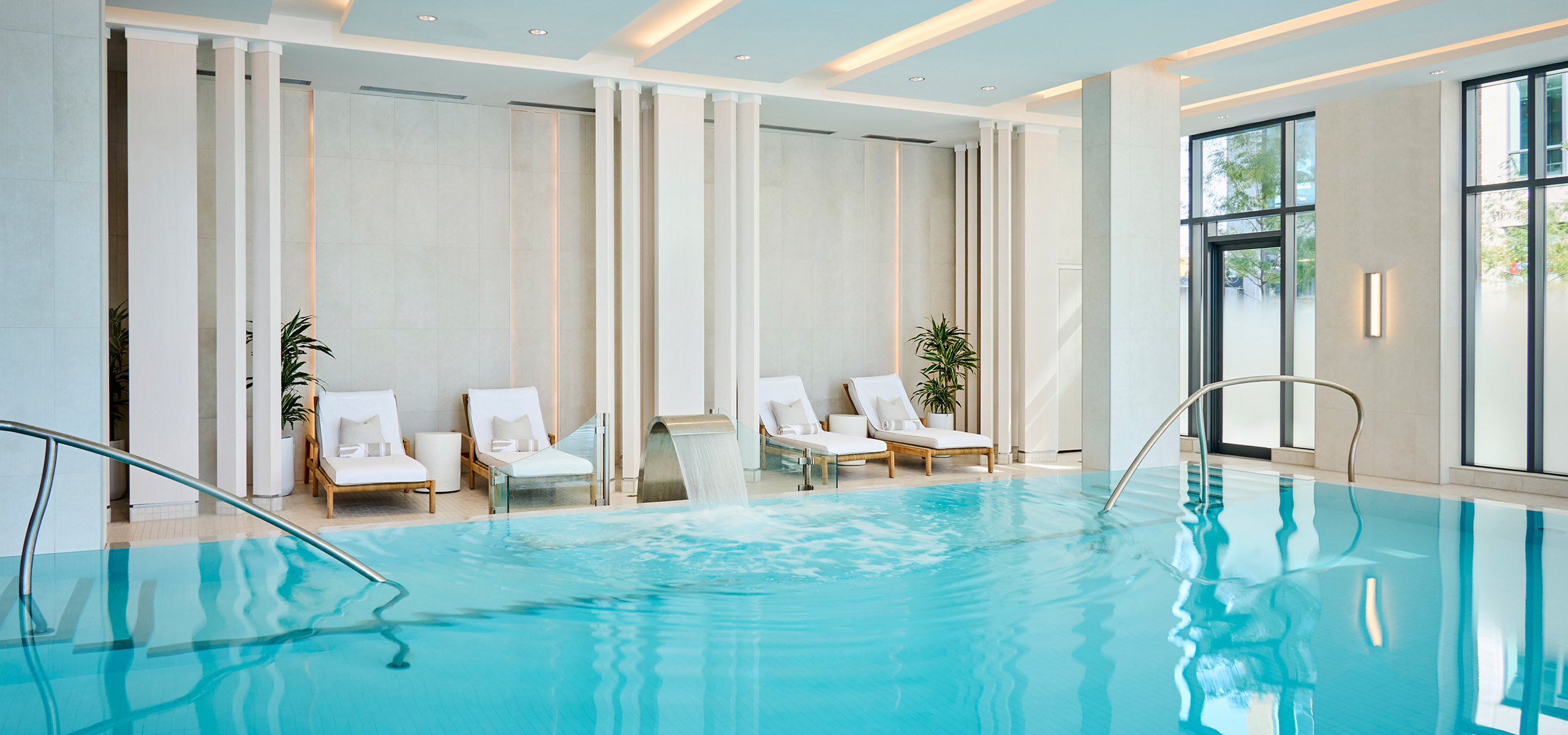 Pool lounge chairs next to beautiful blue water pool at The Pearle Hotel in Burlington Ontario