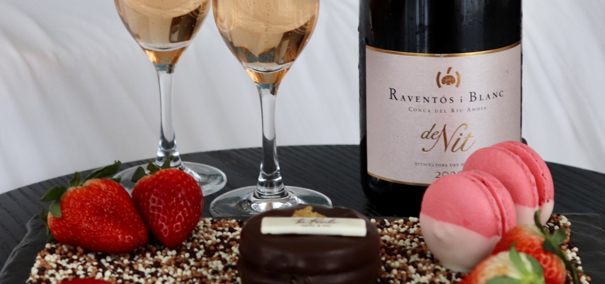 Close up photo of two champagne glasses and a spread of desserts