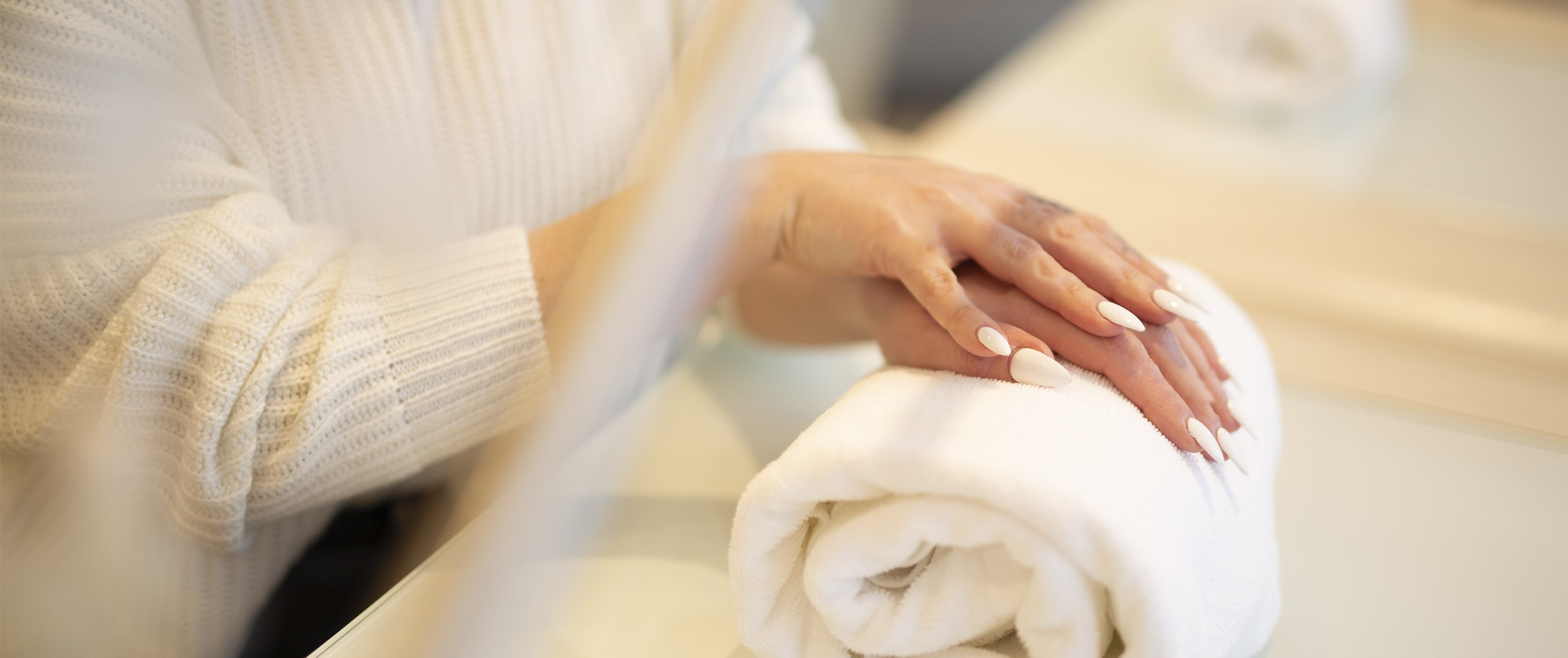 Undistinguishable person with their hands placed gently on a rolled towel after a manicure