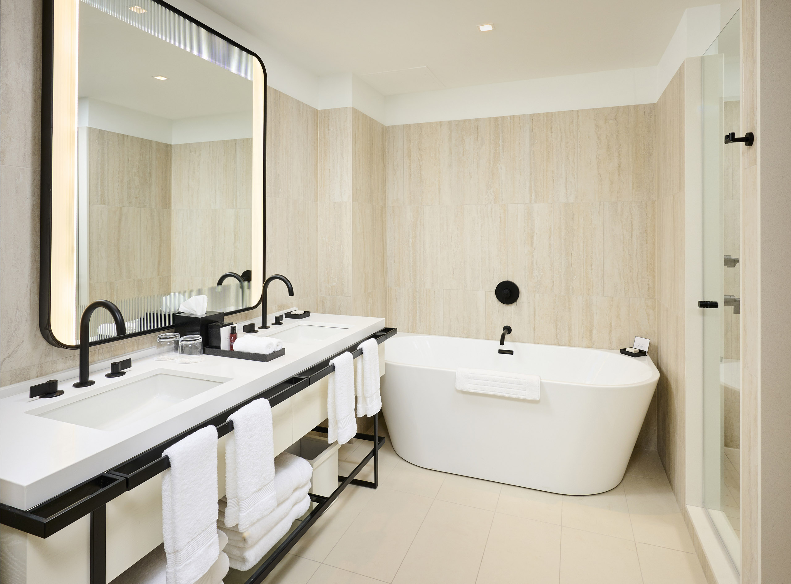 Large, white soaking tub and modern vanity in the Studio Suite room at The Pearle Hotel