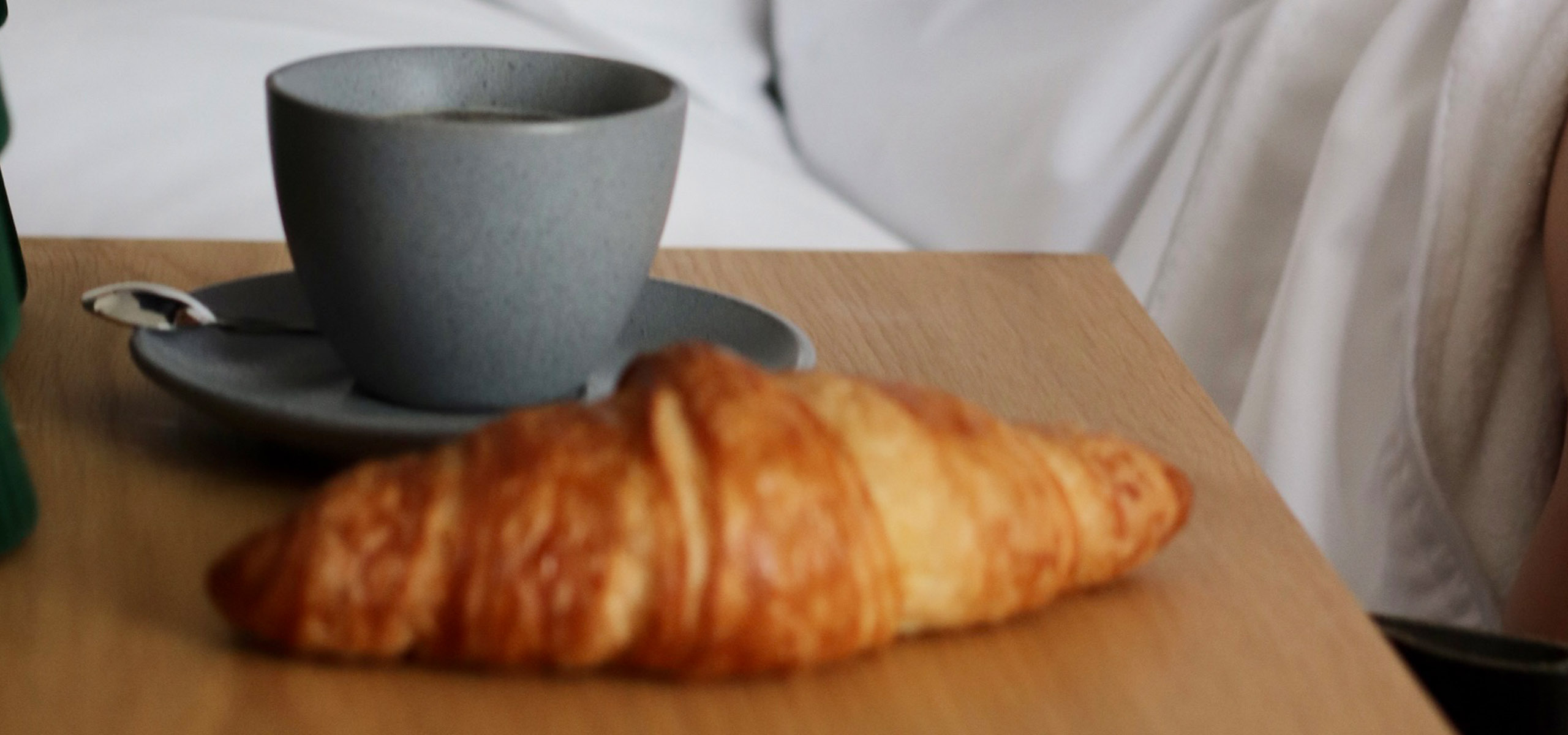 Close up image of a croissant and coffee mug in a hotel suite