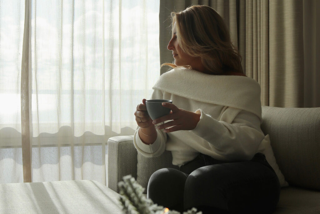 Women sitting on sofa with mug of coffee looking to her right